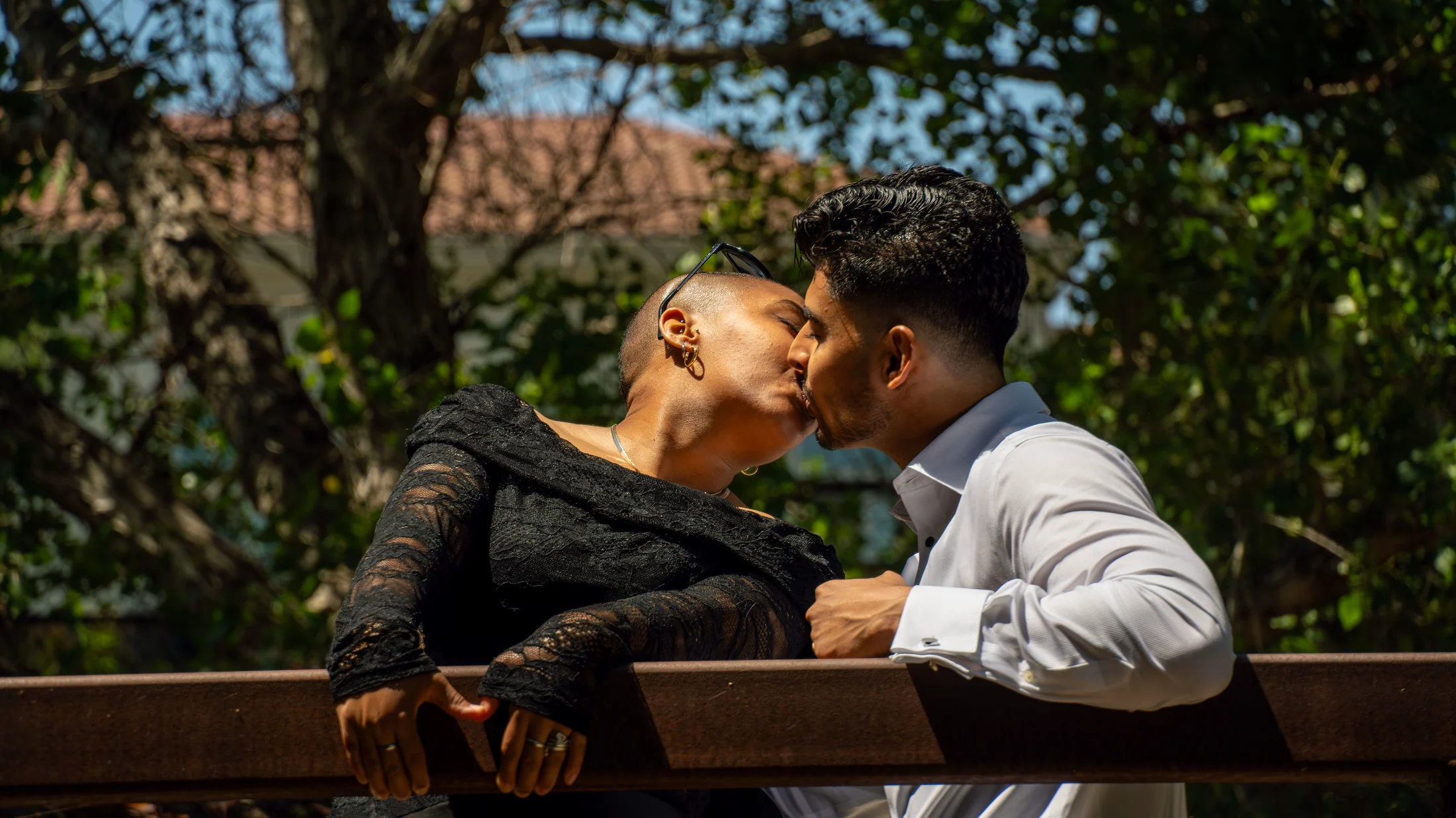 Akshat and Jade kissing across a park bench