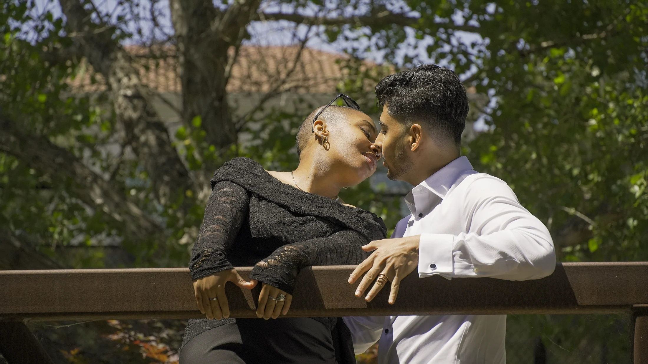 Jade leaning toward Akshat for a kiss beneath the trees