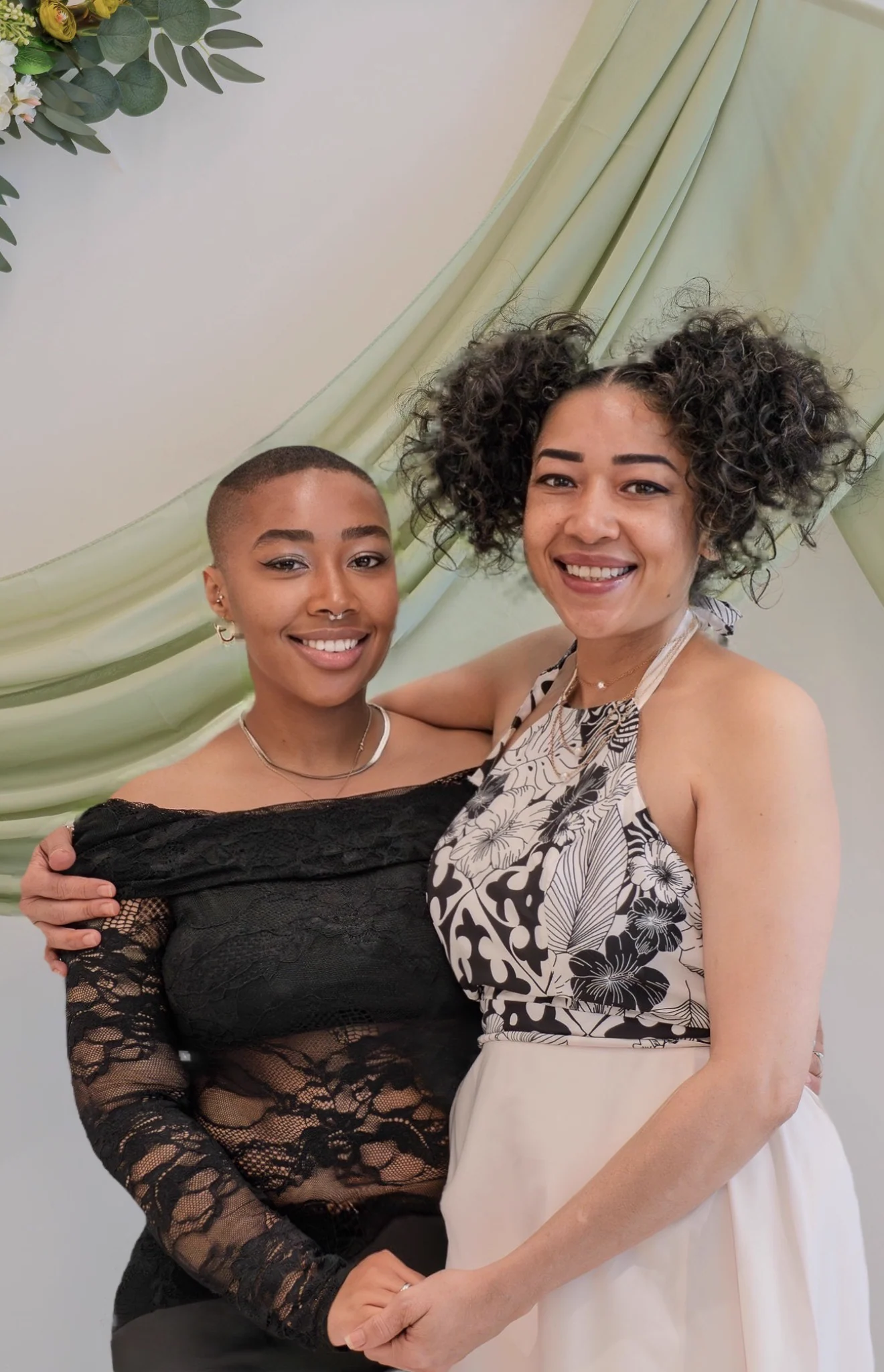 Jade standing with her mother beneath a green floral drape